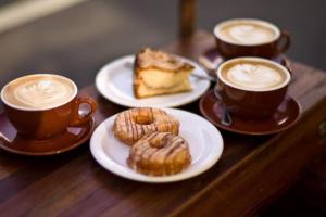 a table with three cups of coffee and a plate of cake at Bayside Bungalow in Cheltenham