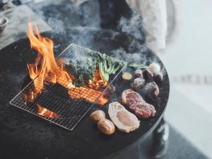 a grill with meat and vegetables on it at Premium villa glamping log cabin with stars and bonfire in Hokuto