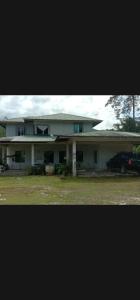 a large white house with a car parked in front of it at Mulu Helena Homestay in Mulu