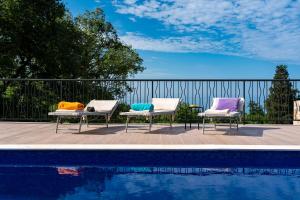 three chairs with colorful pillows sitting next to a pool at Villa Mattson in Budva