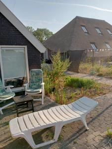 a white bench and a chair and a house at Tiny House Aqualinde in Breda