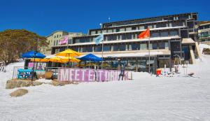 a hotel on the beach with umbrellas in the snow at Stillwell Hotel in Charlotte Pass