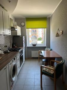 a kitchen with a table and a kitchen with a stove and a window at Atmodas 70 in Jelgava