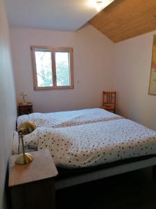 a bedroom with a bed and a table with a lamp at LES ANTHOCYANES in Champagny