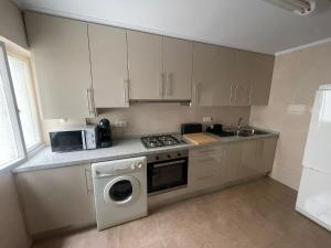 una cocina con lavadora y microondas en BegoÑa Suite, en Gijón 16 fotos más