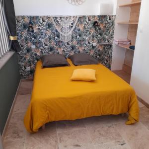 Una cama amarilla con dos almohadas encima. en Villa Castellane en Bauduen