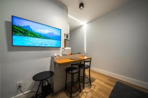 Habitación con bar con taburetes y TV en la pared en Studio247 Experience by Haven en Brasilia