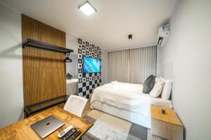a bedroom with a bed and a desk with a laptop at Studio247 Experience by Haven in Brasilia