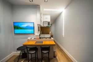 a kitchen with a table with chairs and a tv on the wall at Studio247 Experience by Haven in Brasilia
