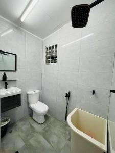 La salle de bains est pourvue de toilettes, d'un lavabo et d'une baignoire. dans l'établissement Ruwa Homestay, à Jitra