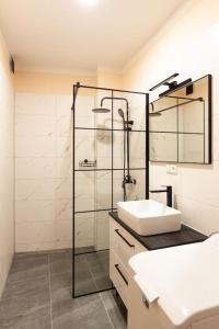 a white bathroom with a sink and a shower at Vysoká Apartman EMF/STP in Bratislava