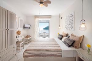 a white bedroom with a bed and a desk and a window at Nafsika Villas in Kerveli