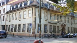 een gebouw in een straat waar auto's voor geparkeerd staan bij Stadthaus Zimmer 6 neben dem REM-Museum in Mannheim Mitte in Mannheim