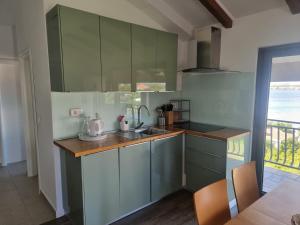 - une cuisine avec des placards verts, un évier et une table dans l'établissement Apartments Faust, à Prvić Šepurine