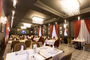 a dining room with tables and chairs and chandeliers at Leon Hotel Spa Ganja in Ganja