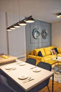 sala de estar con mesa y sofá amarillo en The Impressive Apartment, en Trebinje