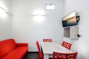 een woonkamer met een rode bank en een tafel en stoelen bij Aparthotel Ganzirri Messina in Messina