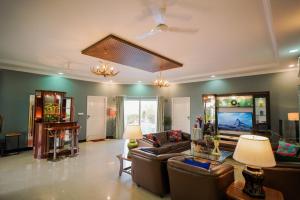 Woodlands Cottage - Luxury stay في جودبور: غرفة معيشة مع أرائك وتلفزيون بشاشة مسطحة