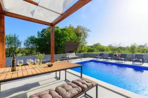 een patio met een tafel en stoelen naast een zwembad bij Villa Balun in Orihi - 3 bedrooms - pool - garden - sauna in Orihi