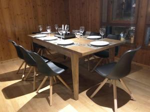 a wooden table with chairs and wine glasses on it at L'Appart' in Les Deux Alpes