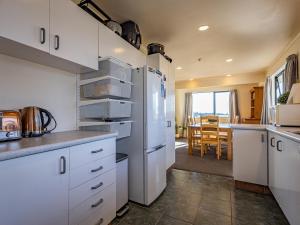 una cucina con armadietti bianchi e frigorifero di Three Peak Lodge - National Park Holiday Home a National Park