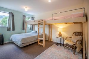 a bedroom with two bunk beds and a chair at Links Lifestyle - Duvauchelle Holiday Home in Duvauchelle