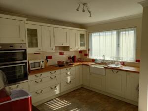 a kitchen with white cabinets and a window at Pet Friendly Beautiful Detached Cottage close to Spurn Point, Easington and Withersea in Hull