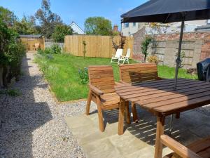 a wooden table and bench with an umbrella at Pet Friendly Beautiful Detached Cottage close to Spurn Point, Easington and Withersea in Hull