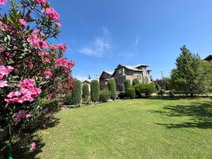 a house with a yard with pink flowers and bushes at Farmhouse - A Luxury Living in Srinagar