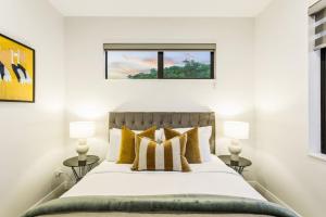 - une chambre avec un lit doté d'oreillers jaunes et d'une fenêtre dans l'établissement Pristine Modern Central Home - Netflix - Heatpump, à Auckland