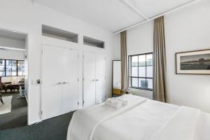Biała sypialnia z dużym łóżkiem i białymi szafkami w obiekcie Gorgeous NY Style Loft in CBD - Netflix Wifi w Auckland