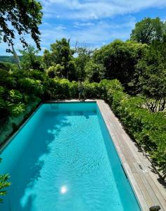une piscine d'eau bleue et d'arbres dans l'établissement L'annexe du domaine de brisset, à Montélimar