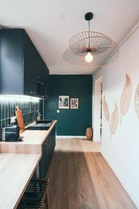 a kitchen with black cabinets and a chandelier at L'Amazonien - Baby-foot et filet de détente ! in Nîmes