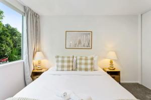 Un dormitorio blanco con una cama grande y una ventana. en Hideaway Apartment with pool and free parking, en Auckland