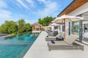 una piscina infinita con sillas y una sombrilla junto a una casa en Villa Mandra - Beautiful 4 Bedroom Luxury Pool Villa KBR2 en Koh Samui