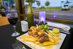 eine Platte mit Garnelen und Pommes frites und ein Glas Wein in der Unterkunft Hospitality Esperance SureStay Collection by Best Western in Esperance