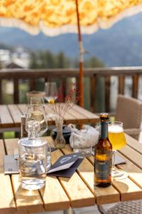 a wooden table with a bottle of beer and glasses at Pension Arosa - Self Check-In in Arosa