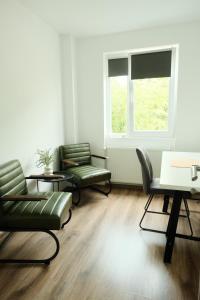 Una sala de estar con sillas y una mesa y una ventana. en Godspeed Artist's Getaway, en Baia Mare