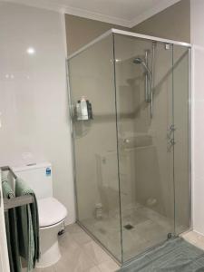 a bathroom with a glass shower with a toilet at oasis by the beach in Glenelg