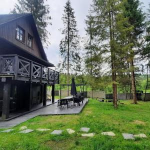 uma casa com um pátio com uma mesa e bancos em Fabryka Snów loft w sercu Beskidów em Istebna
