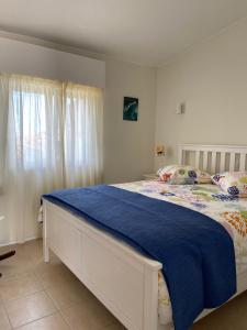 een slaapkamer met een groot bed en een blauw dekbed bij Apartamento na Vila Senhora da Rocha in Porches