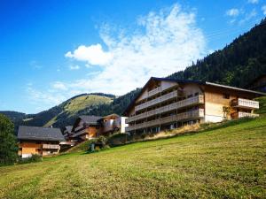 a building on a hill next to a field at Résidence Néméa Le Grand Lodge in Châtel