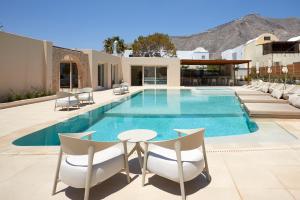 a swimming pool with chairs and a table in front of a house at Apricus in Perissa