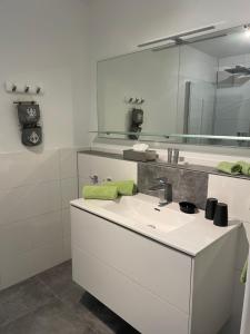 a white bathroom with a sink and a mirror at Winzer Lounge Ferienwohnung in Dernau +9 photos