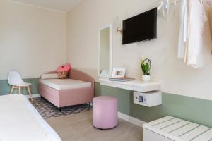 ein Zimmer mit einem Bett, einem Stuhl und einem Fernseher in der Unterkunft Pan di Zenzero Icecream Hotel in Rimini
