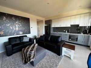 a living room with a black couch and a kitchen at Entire One Bedroom Apartment, Penrith in Kingswood