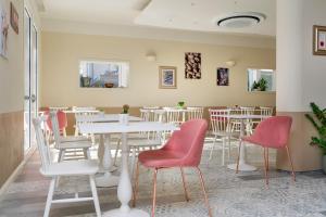 un restaurante con mesas blancas y sillas rojas en Pan di Zenzero, en Rímini