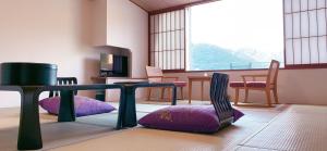 a room with two chairs and a table and a tv at Naruko Kanko Hotel in Osaki