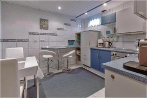 a large kitchen with white appliances and blue cabinets at Ferienwohnung Am Berg in Pinzberg