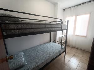 Ce dortoir comprend 2 lits superposés et une fenêtre. dans l'établissement Beach House Roda de Bera, à Roda de Bará